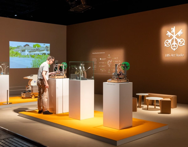 Art exhibition stand with art objects on display on top of orange event carpet